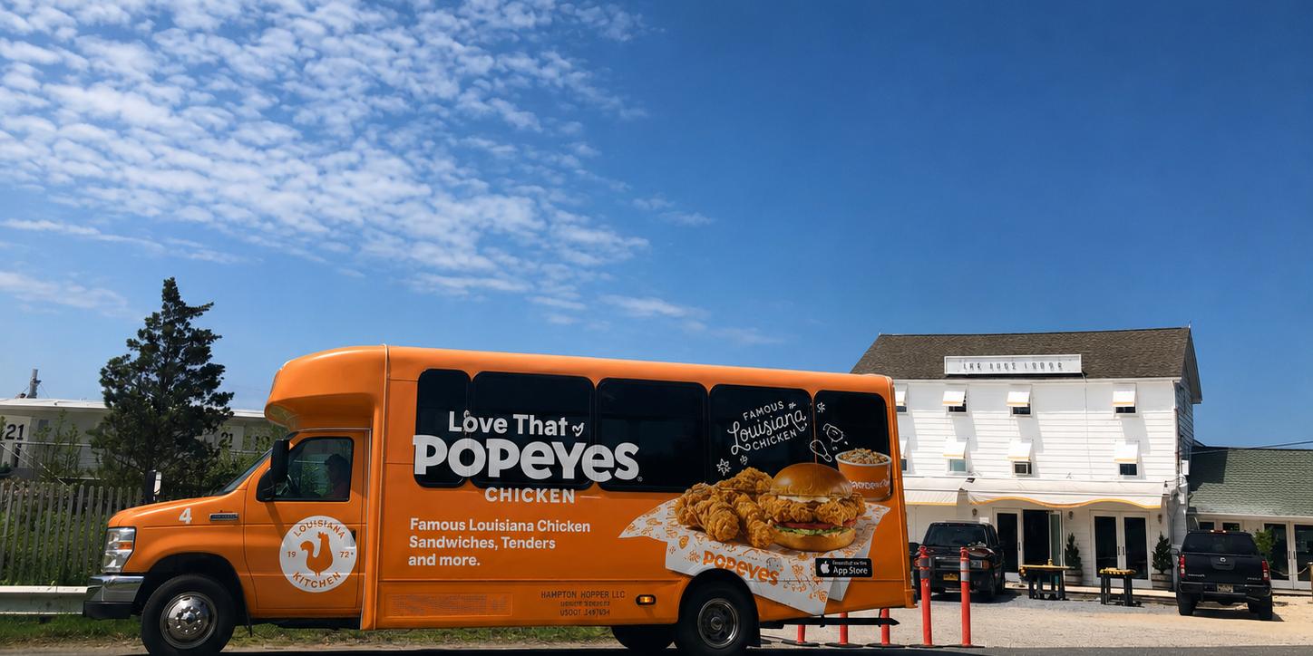 A Popeyes-wrapped Hampton Hopper bus in front of the Surf Lodge in Montauk